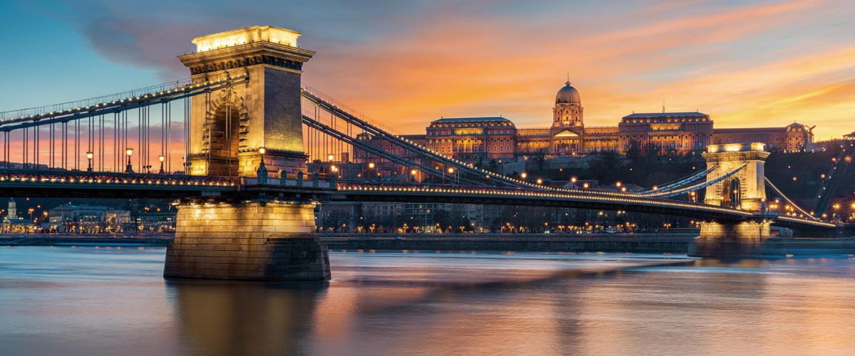 A view across the Danube River at dusk with Buda Castle and Chain Bridge illuminated, Budapest